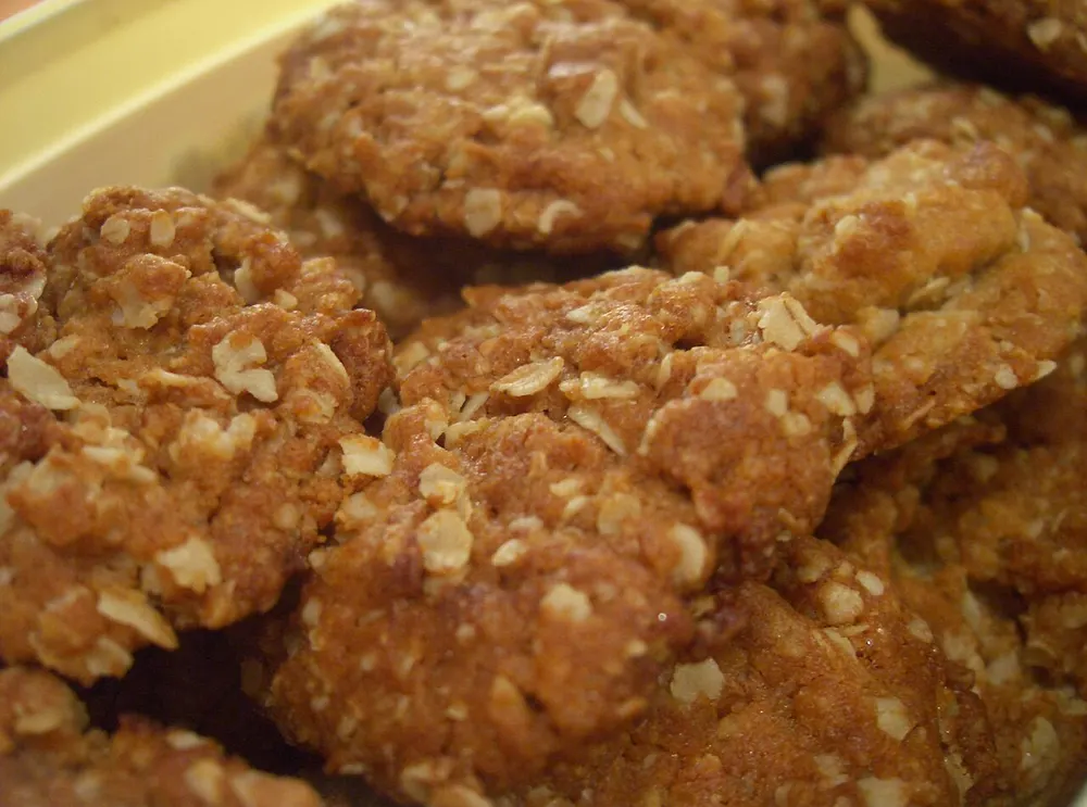 Golden oat-and-coconut Anzac biscuits seen close up in a tin