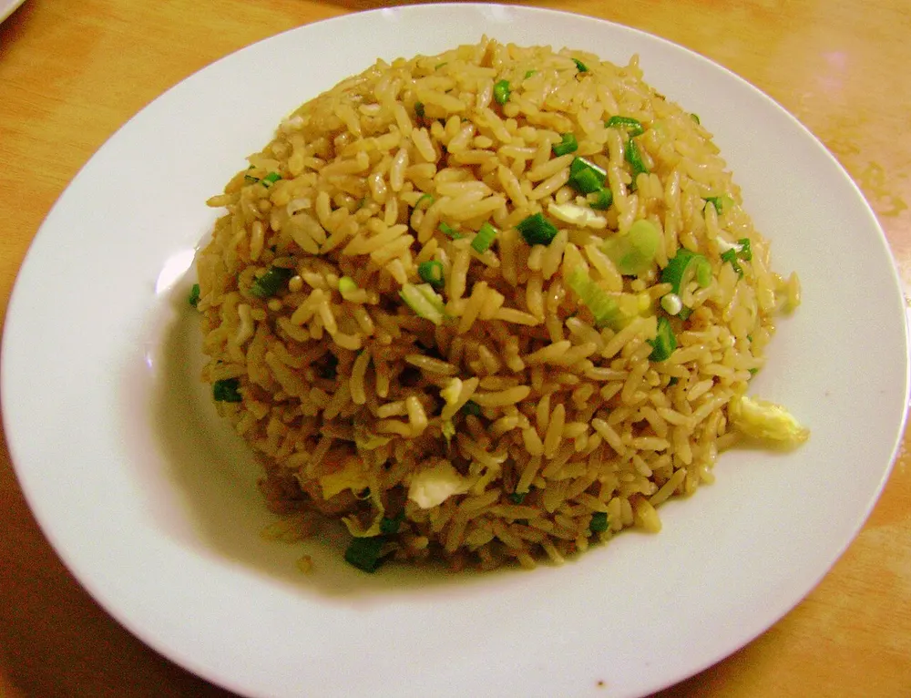 A plate of arroz chaufa — brown fried rice flecked with spring onion and egg