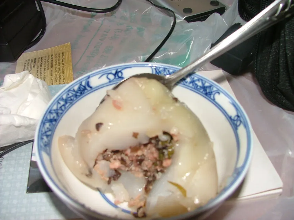 Bánh giò unwrapped in a bowl, the soft rice-flour cake cut open to its pork and mushroom filling