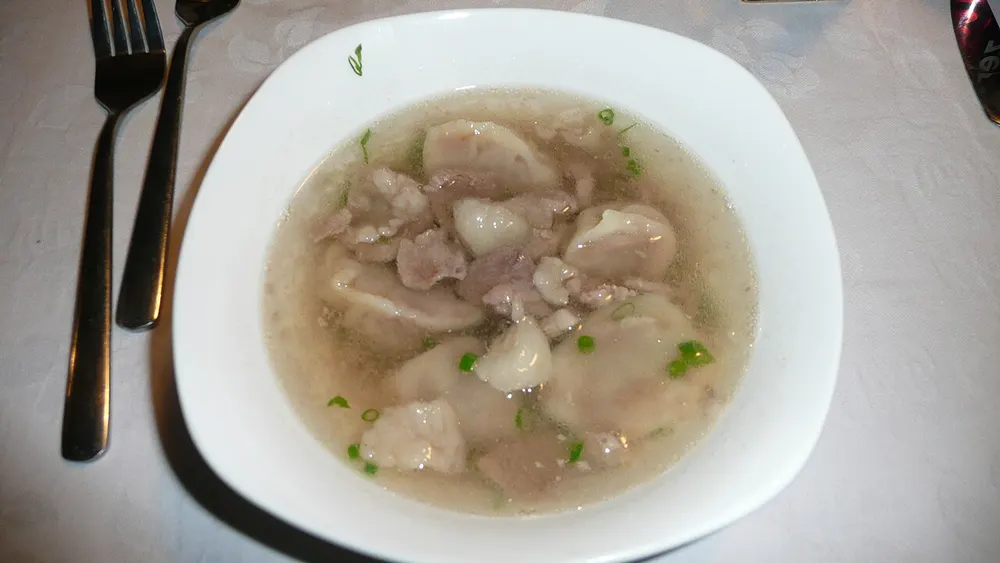 Bansh floating in clear mutton broth with pieces of meat and sliced spring onion