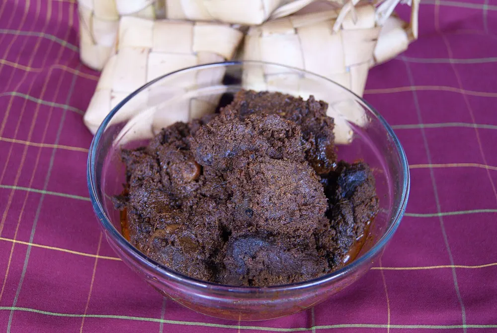 A bowl of dark, dry beef rendang with the spice paste clinging to the meat