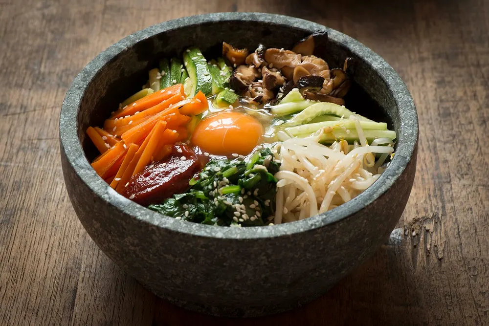 Dolsot bibimbap topped with vegetables, beef and an egg