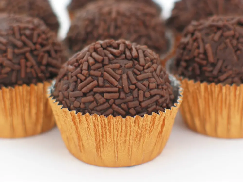 Chocolate brigadeiros coated in sprinkles, in gold foil cups
