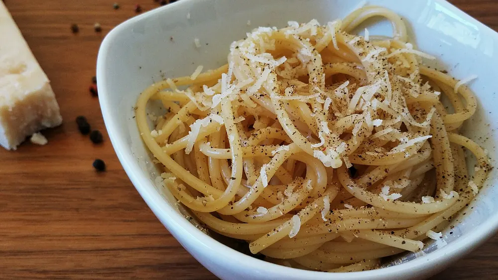 A bowl of spaghetti cacio e pepe dusted with pecorino and black pepper