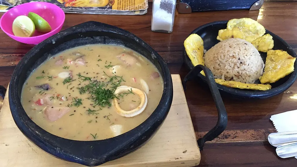 Cazuela de mariscos in a clay pot with coconut rice and patacones alongside