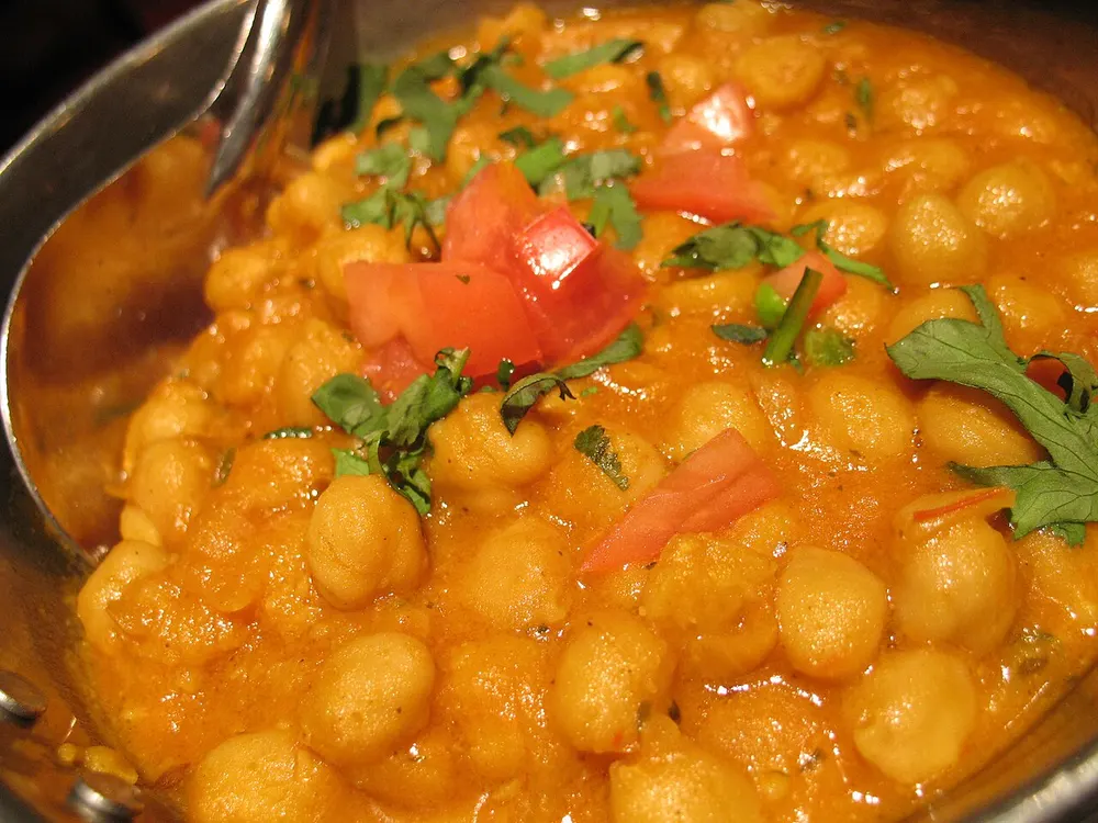Chickpeas simmered in a tangy orange tomato gravy, topped with fresh tomato and cilantro