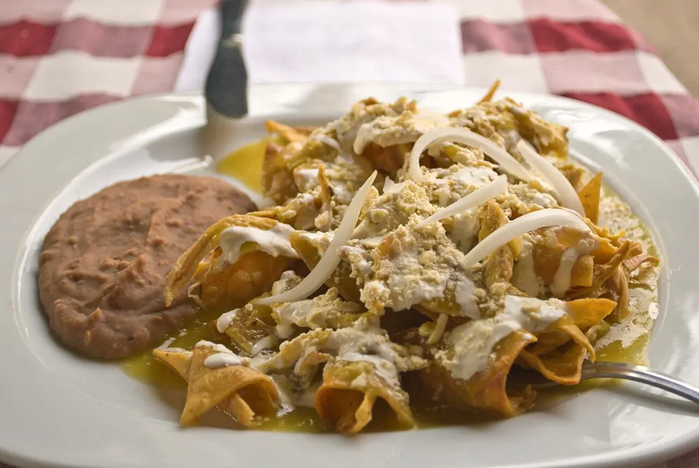 Chilaquiles verdes — tortilla chips simmered in green salsa with cream and cheese