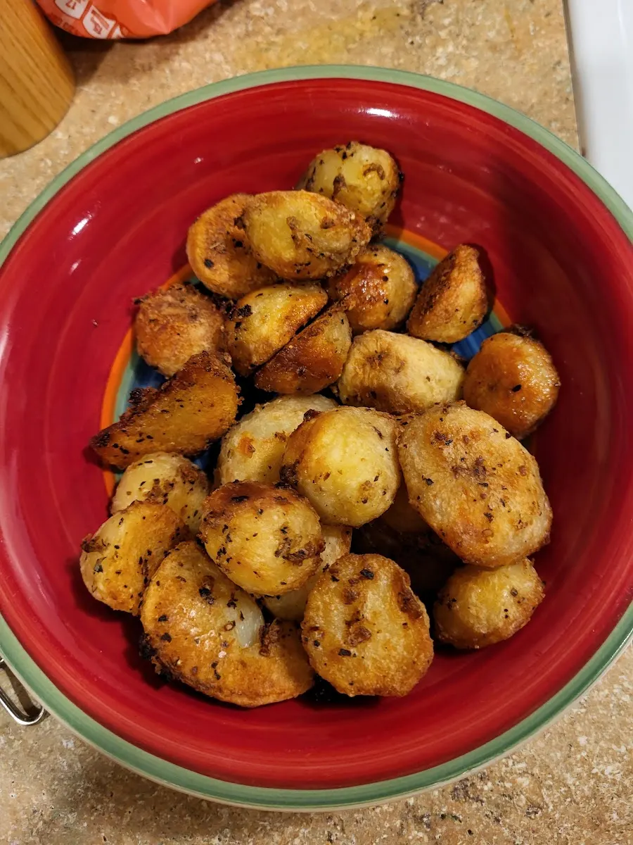 A bowl of roast potatoes, golden and crisp-edged, flecked with herbs