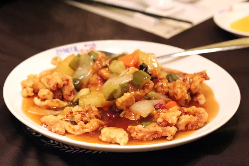 A plate of tangsuyuk — fried pork under a glossy sweet-and-sour sauce with vegetables