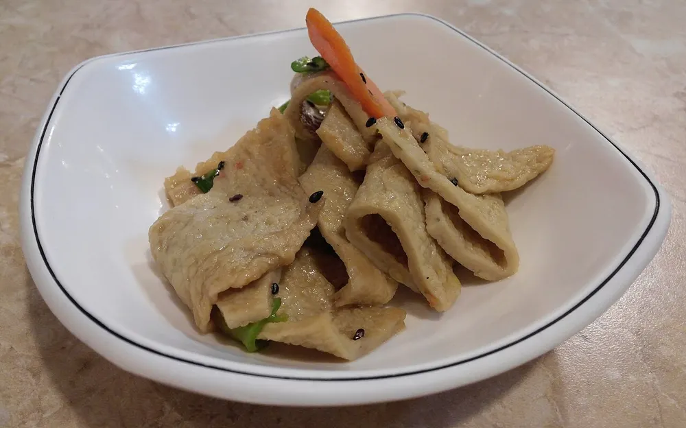 A white dish of eomuk-bokkeum — stir-fried fish cake strips with carrot, green pepper and sesame seeds