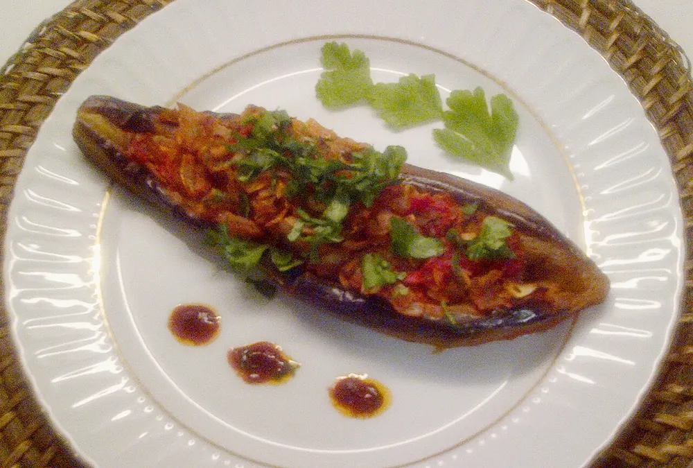 A whole braised eggplant stuffed with onion and tomato in olive oil
