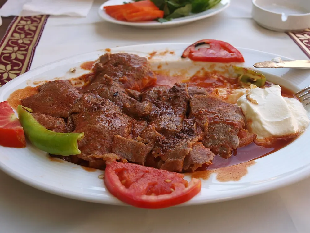 Sliced döner over bread under tomato sauce and browned butter with yogurt