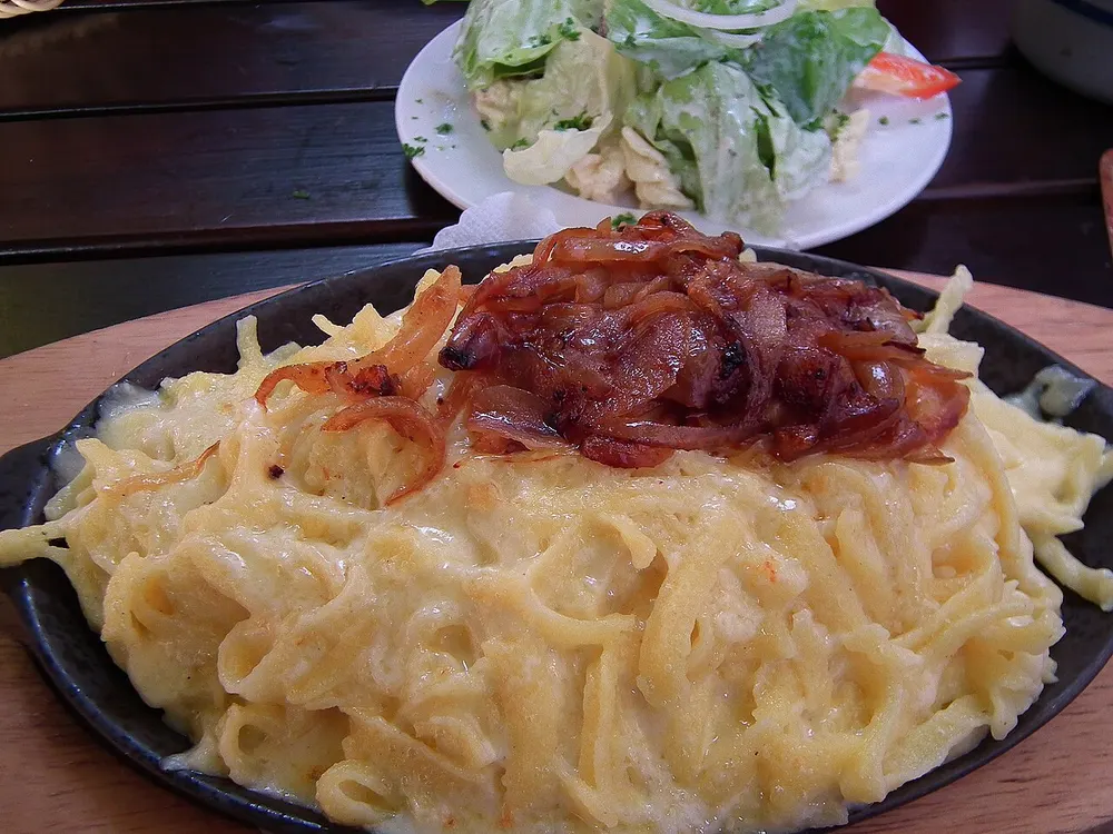 Käsespätzle — Swabian cheese noodles topped with caramelized onions, with a side salad