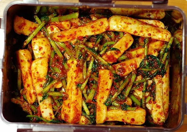 A tub of chonggak-kimchi — small whole radishes with their green tops in red seasoning