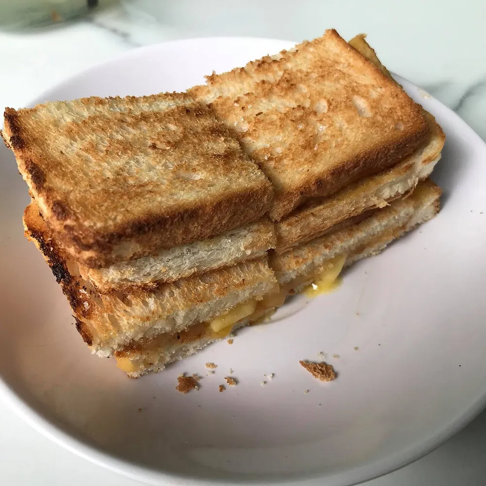 Toasted white bread halves filled with coconut kaya jam and butter on a white plate