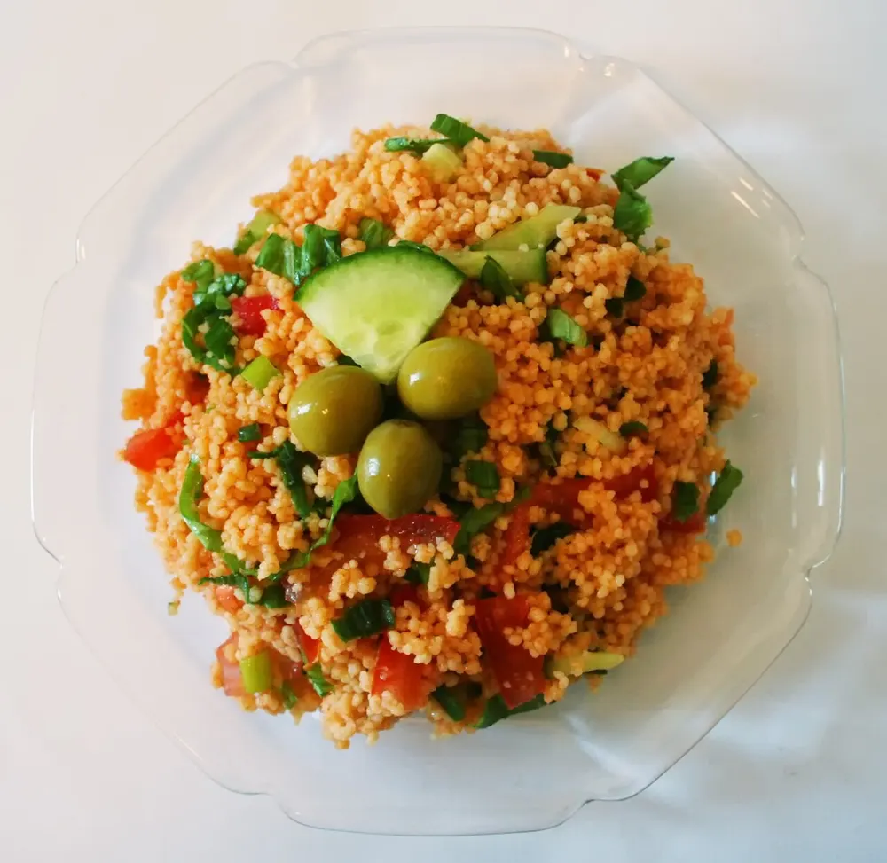 A red bulgur salad with cucumber, tomato, herbs and olives