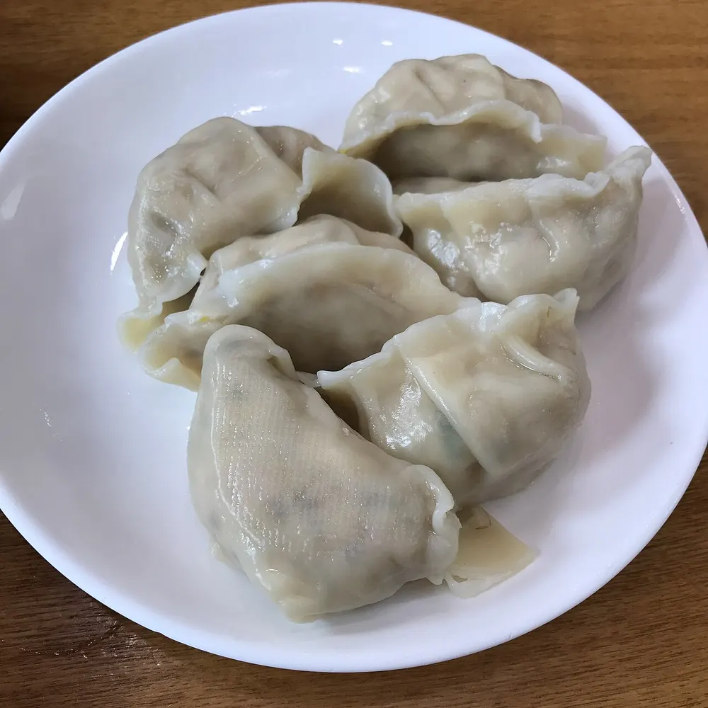 A plate of steamed Korean mandu, folded into half-moons