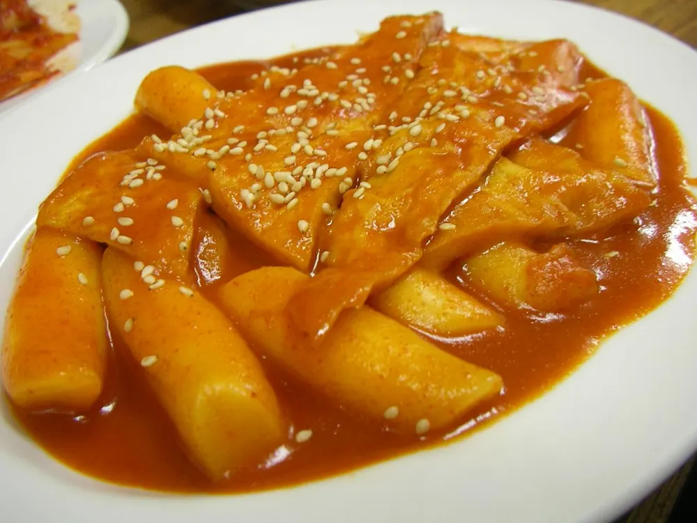 A plate of tteokbokki — rice cakes and fish cake in a glossy red sauce