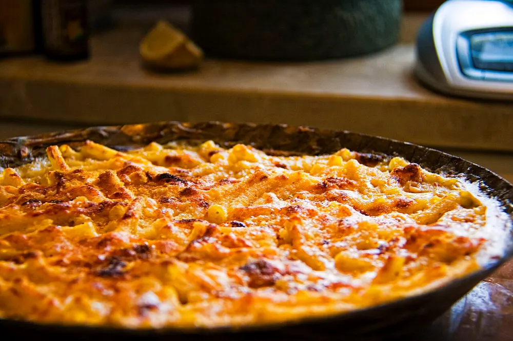 A baking dish of macaroni under a browned, bubbling cheese crust