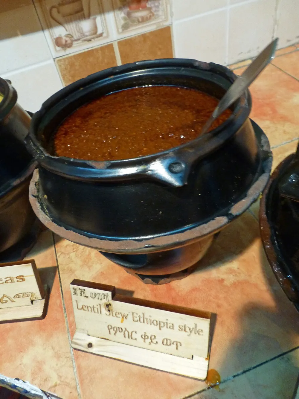 Red lentil misir wot in a black clay pot on an Ethiopian buffet