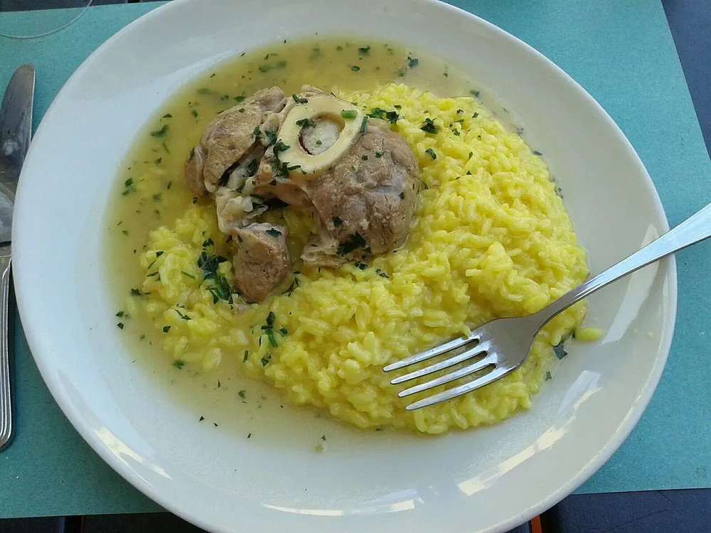 An ossobuco with its marrow bone, served alongside saffron risotto alla milanese