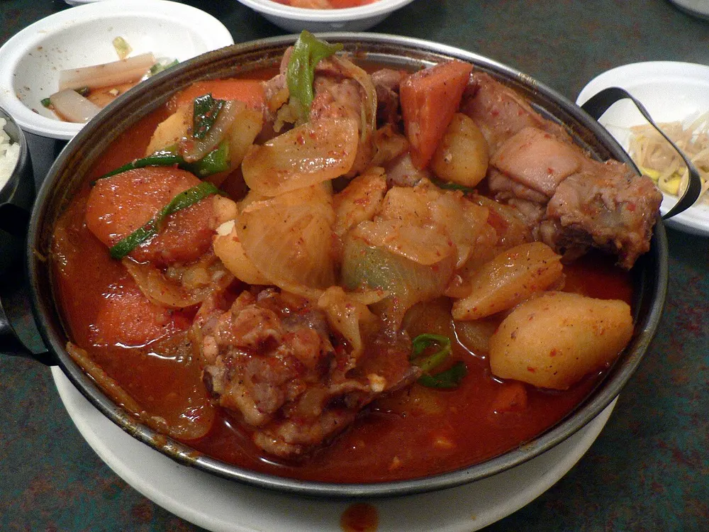 A pot of dak-bokkeum-tang: chicken, potato and carrot in a red spicy broth