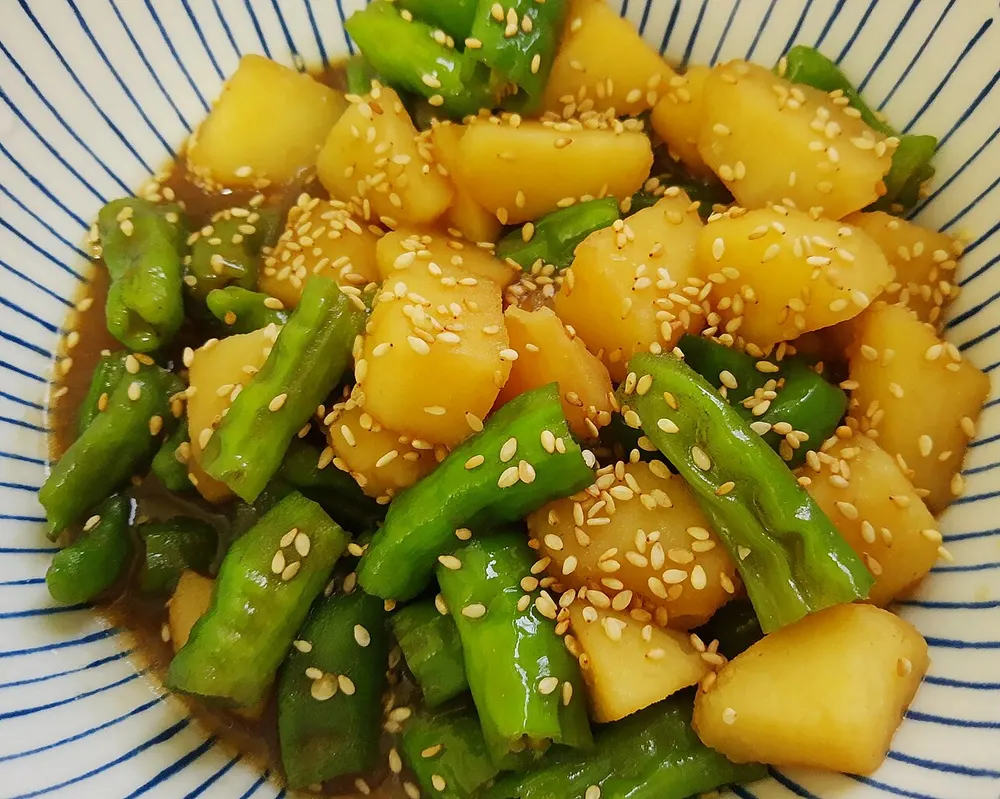 A bowl of gamja-jorim — potato cubes braised in soy with shishito peppers and sesame seeds