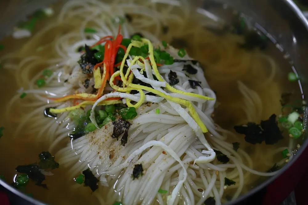 A bowl of janchi-guksu — thin somyeon noodles in clear broth topped with egg ribbons, scallion and seaweed