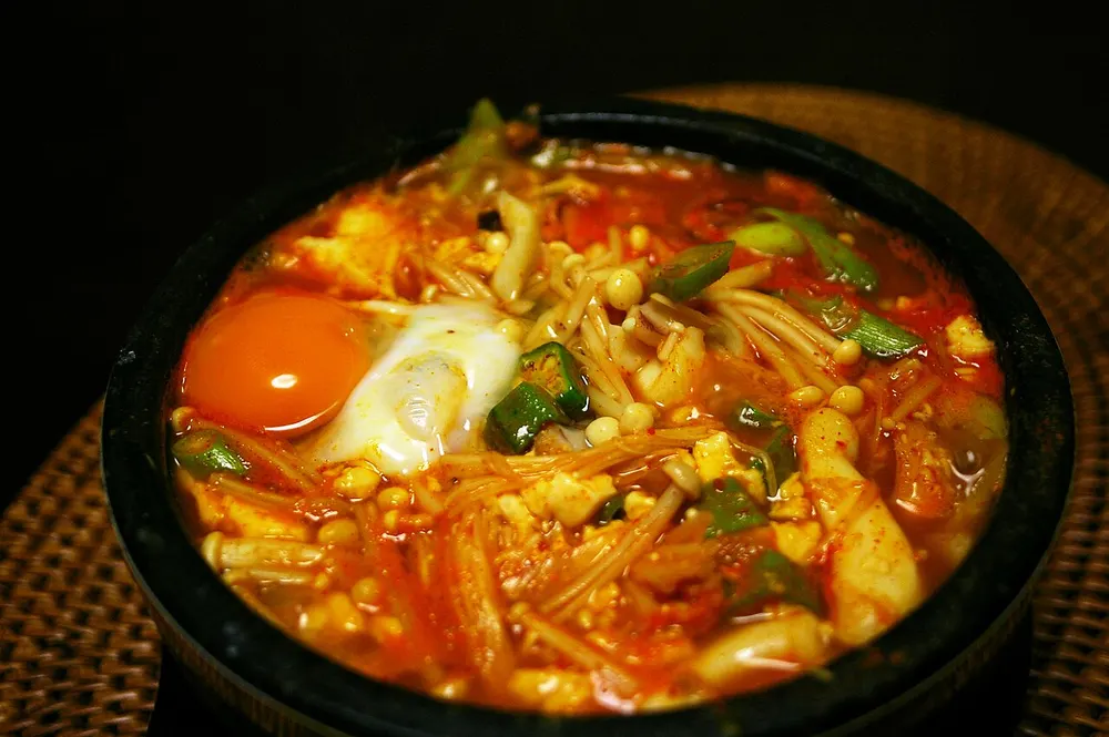 A bubbling ttukbaegi of sundubu-jjigae with a whole egg on top