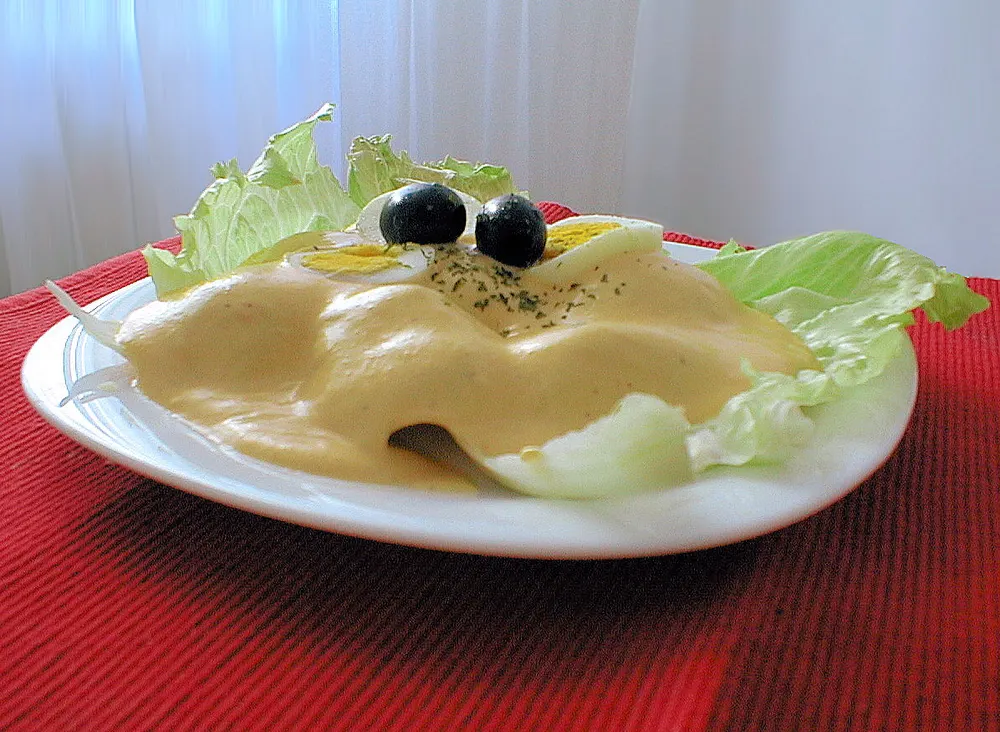 Papa a la huancaina — boiled potatoes under a pale yellow sauce with olives, egg and lettuce