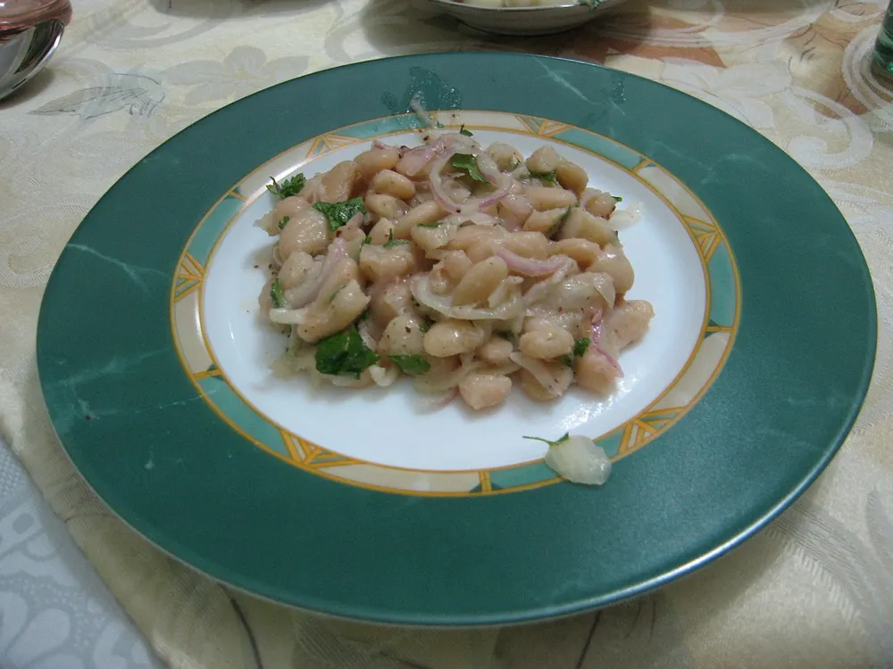 A white-bean salad with red onion and parsley in dressing