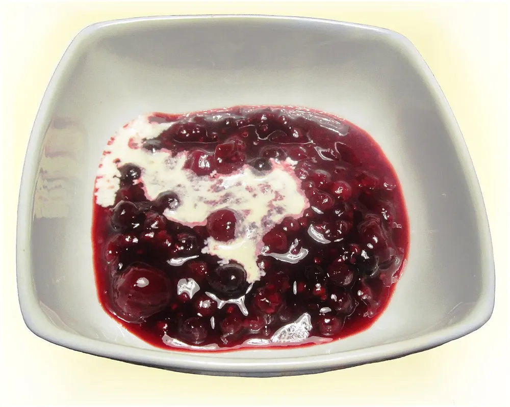 A bowl of red berry rødgrød with cream poured over it
