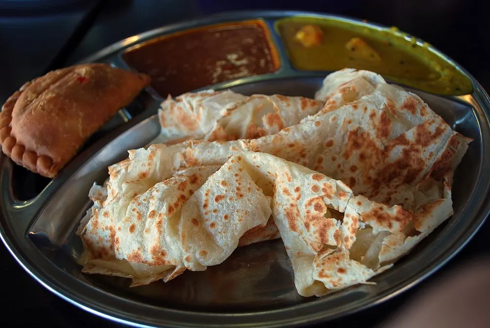 Roti canai — flaky griddled flatbread served with dhal and curry