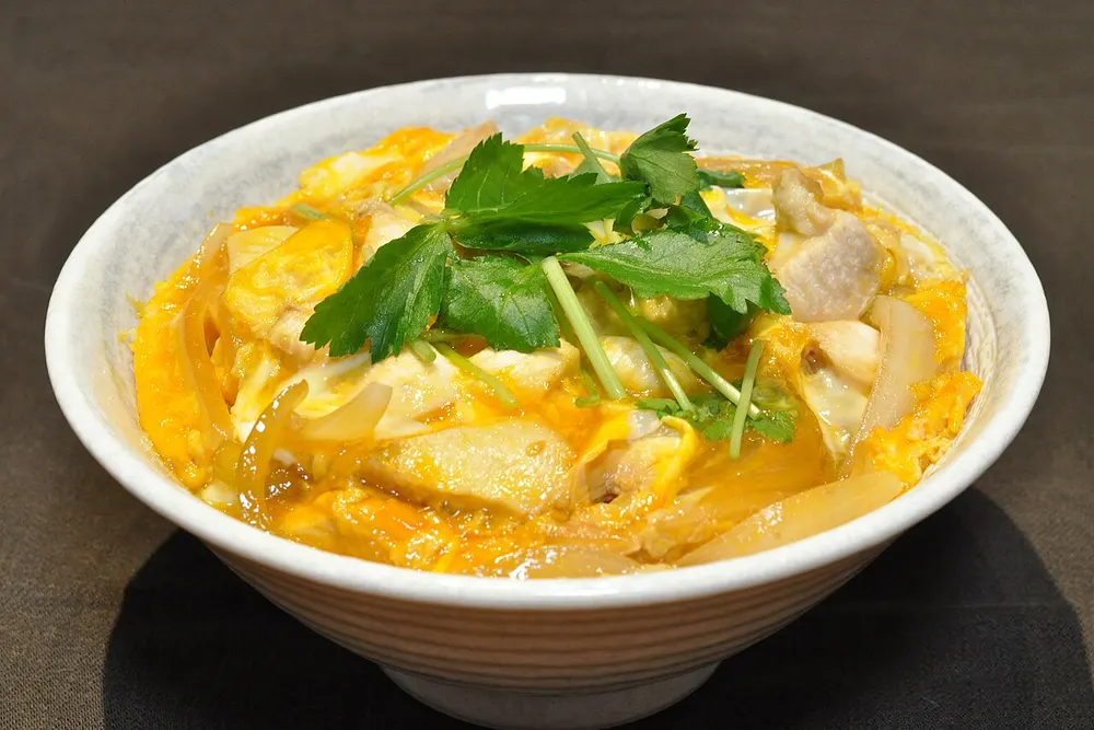 A bowl of oyakodon — chicken and soft egg over rice, topped with mitsuba