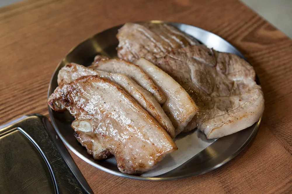 Strips of pork belly grilling on a hot plate