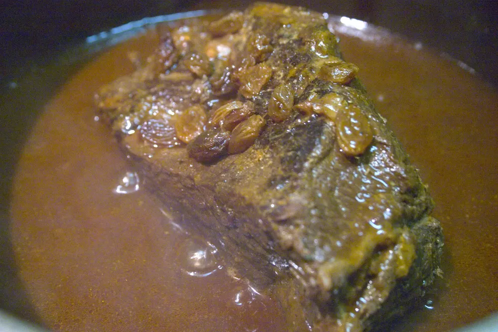 Sauerbraten — marinated beef pot roast braised in a dark sweet-sour gravy with raisins