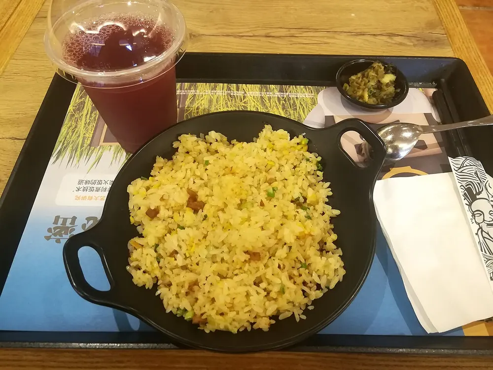 A pan of golden egg fried rice, the grains separate and coated yellow