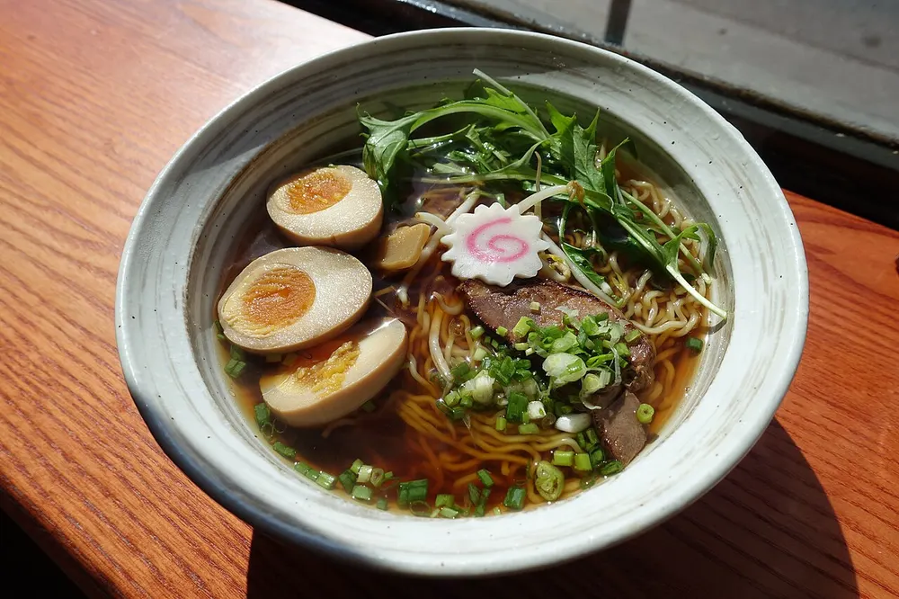 A bowl of shoyu ramen with a clear brown soy broth