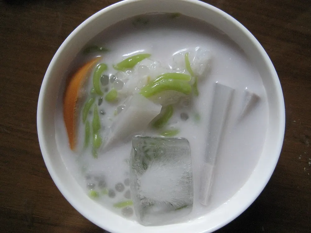 A bowl of shwe yin aye — coconut milk over a block of ice with jelly strips and sago