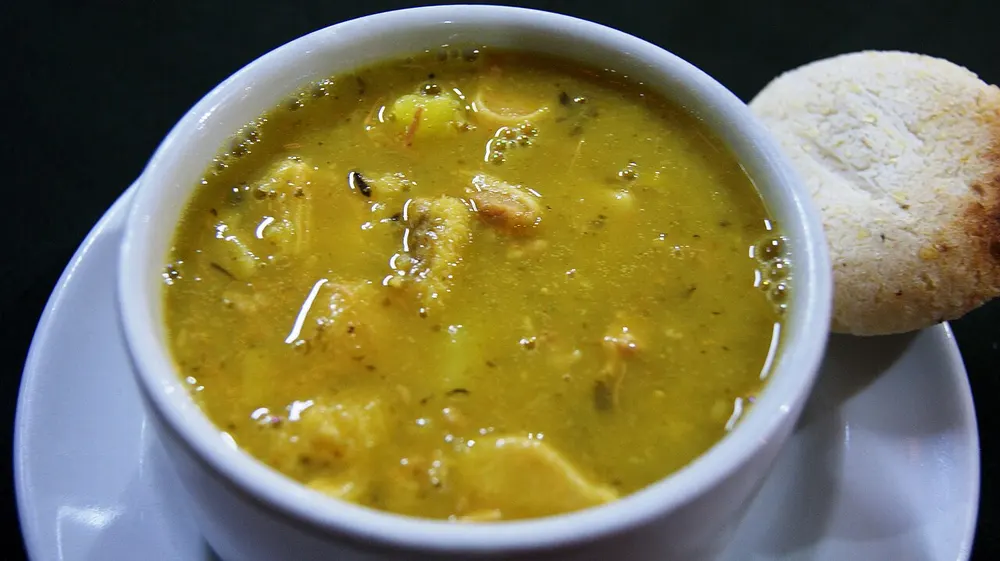 A bowl of sopa de mondongo with an arepa on the side