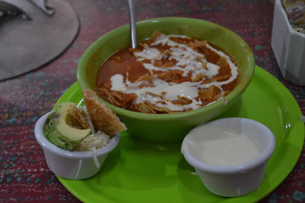 Sopa de tortilla — tomato broth with fried tortilla strips, cream and avocado
