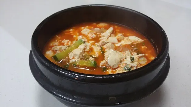 A bubbling ttukbaegi of red sundubu-jjigae with soft tofu and an egg