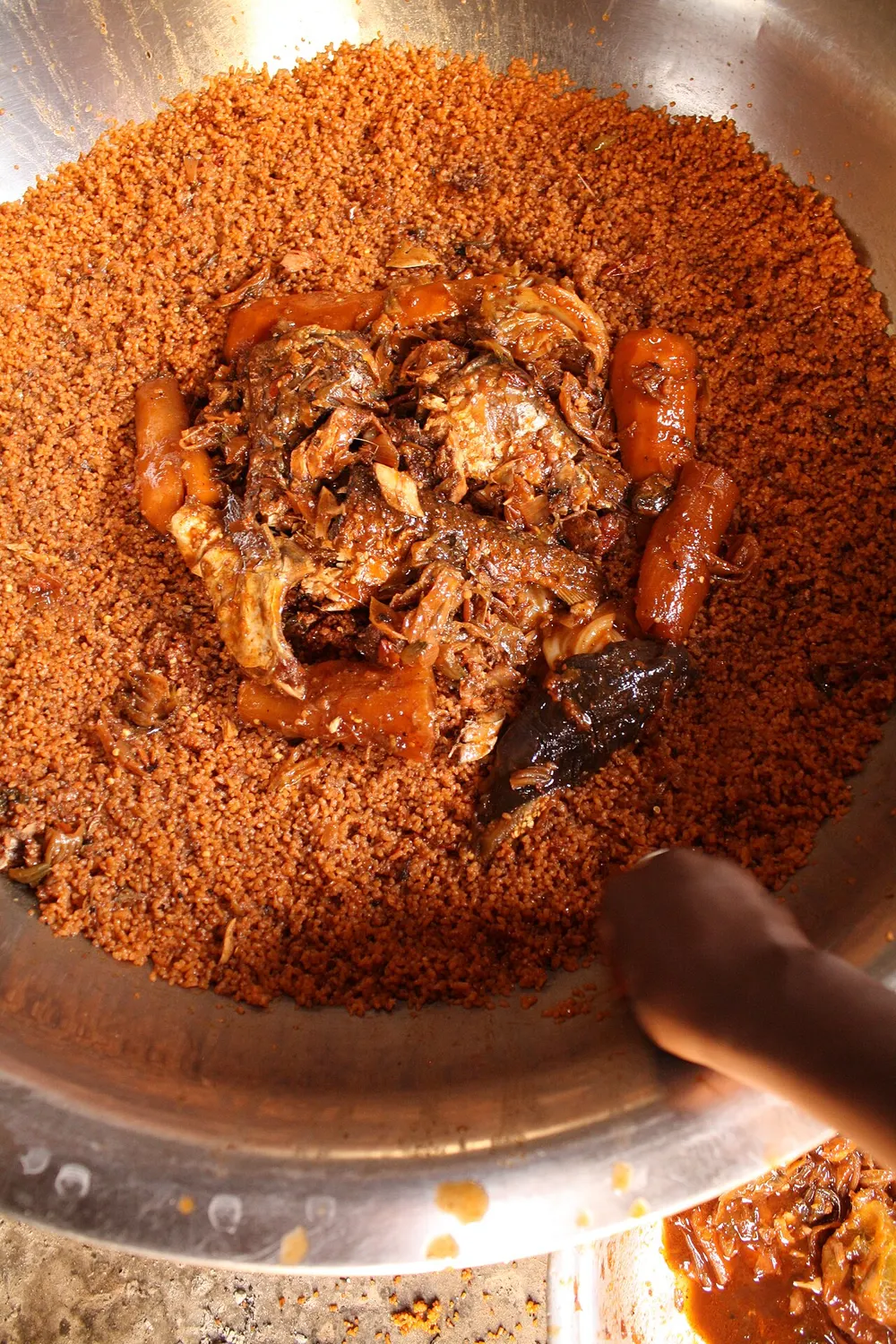 Thieboudienne — red broken rice with stewed fish and vegetables in a shared pan