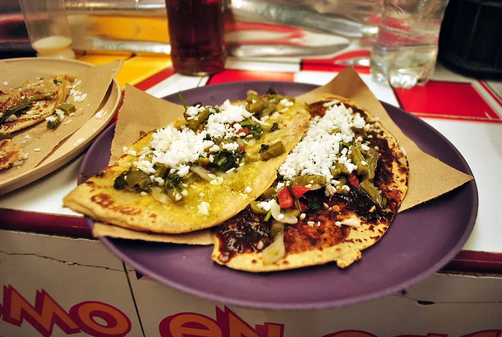 Tlacoyos — oval masa cakes topped with nopales, cheese and salsa