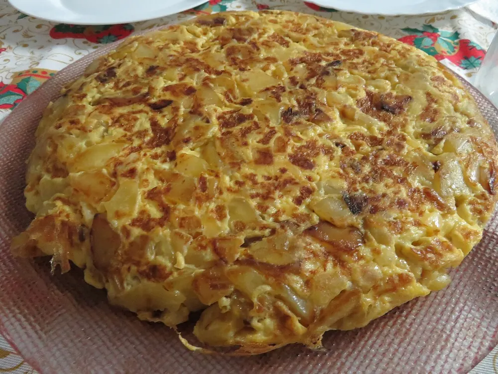 A thick round Spanish tortilla, golden on top, with slices of potato and onion set in the egg