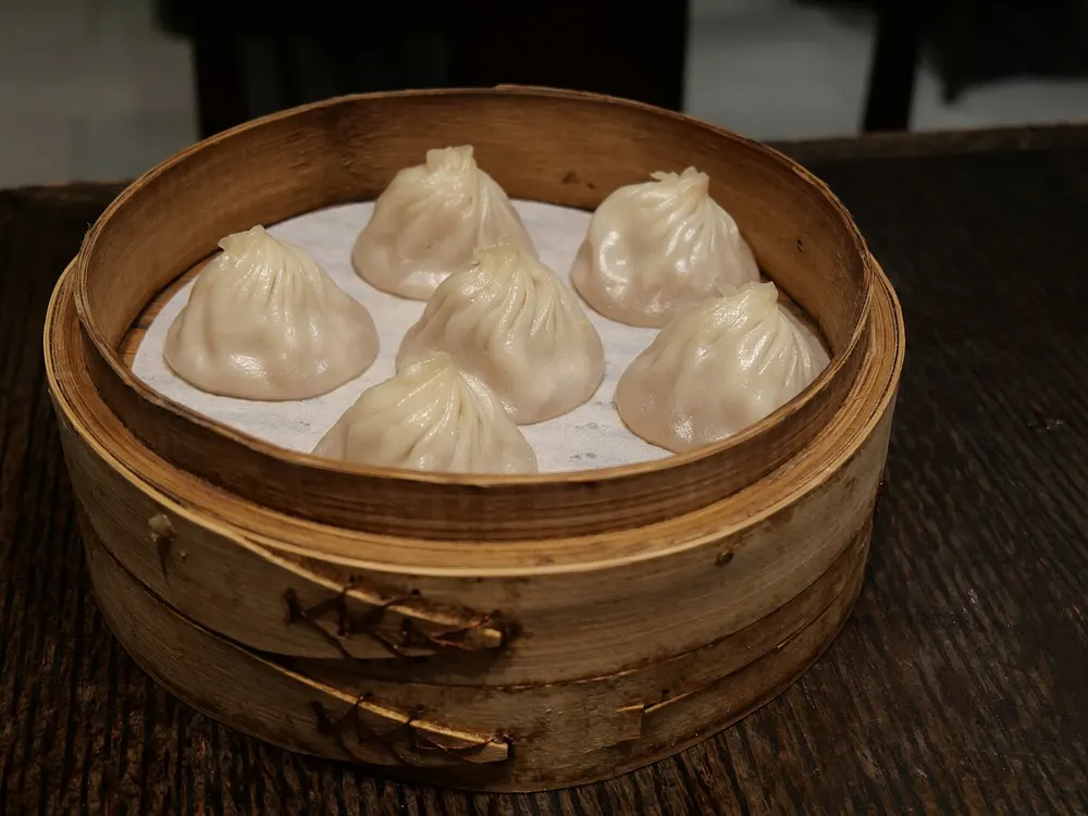 A xiaolongbao soup dumpling held in chopsticks